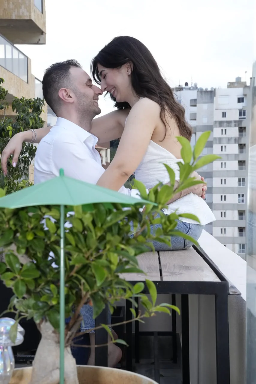 Léa and Elie embracing on a balcony